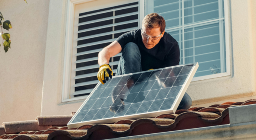 a man installing a second solar panel on his roof