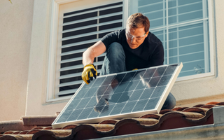 a man installing a second solar panel on his roof