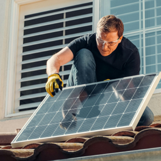 a man installing a second solar panel on his roof